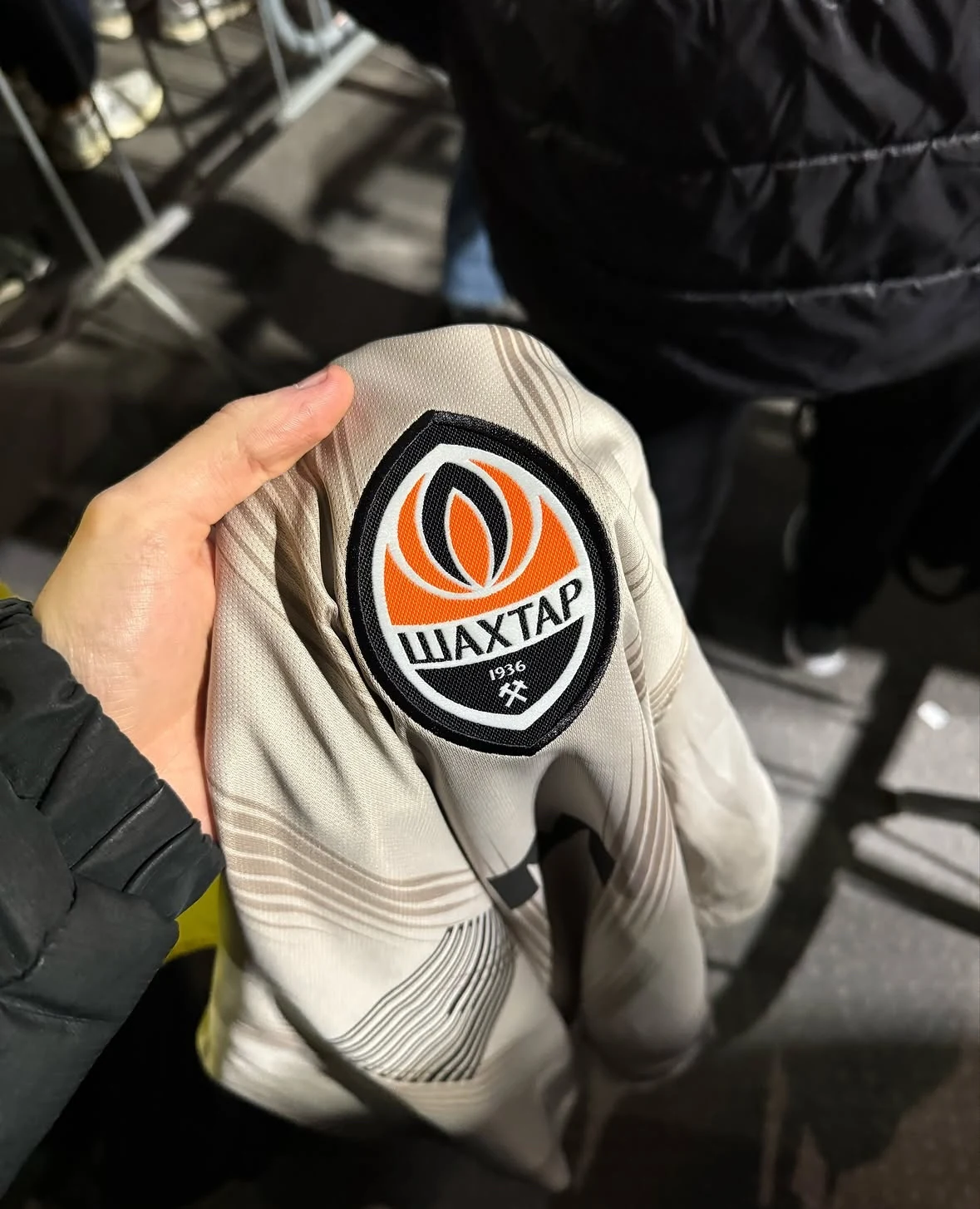 A hand holding a football shirt with the Shakhtar Donetsk crest.