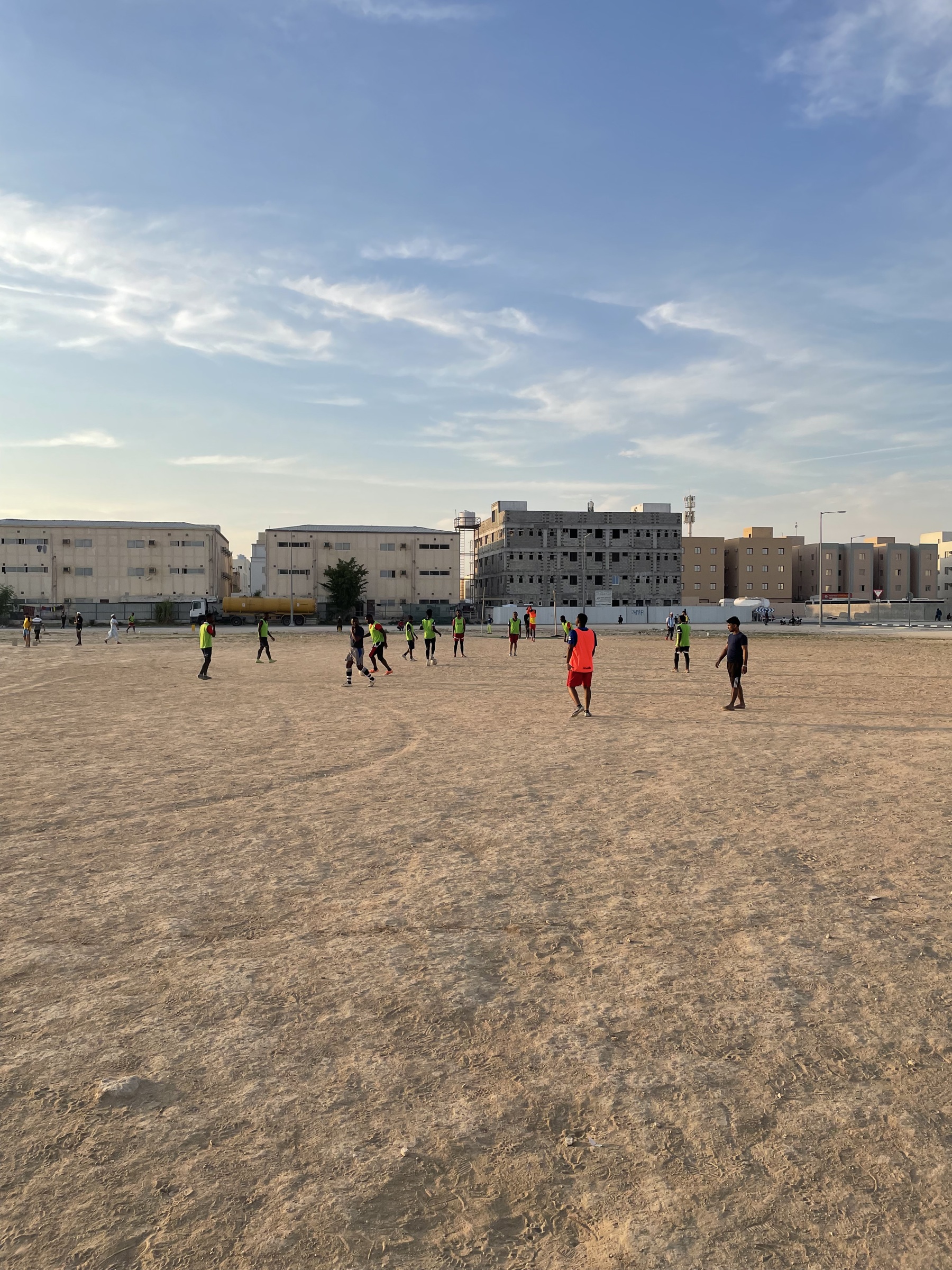 Players on a sandy football pitch in Umm Salal, Qatar
