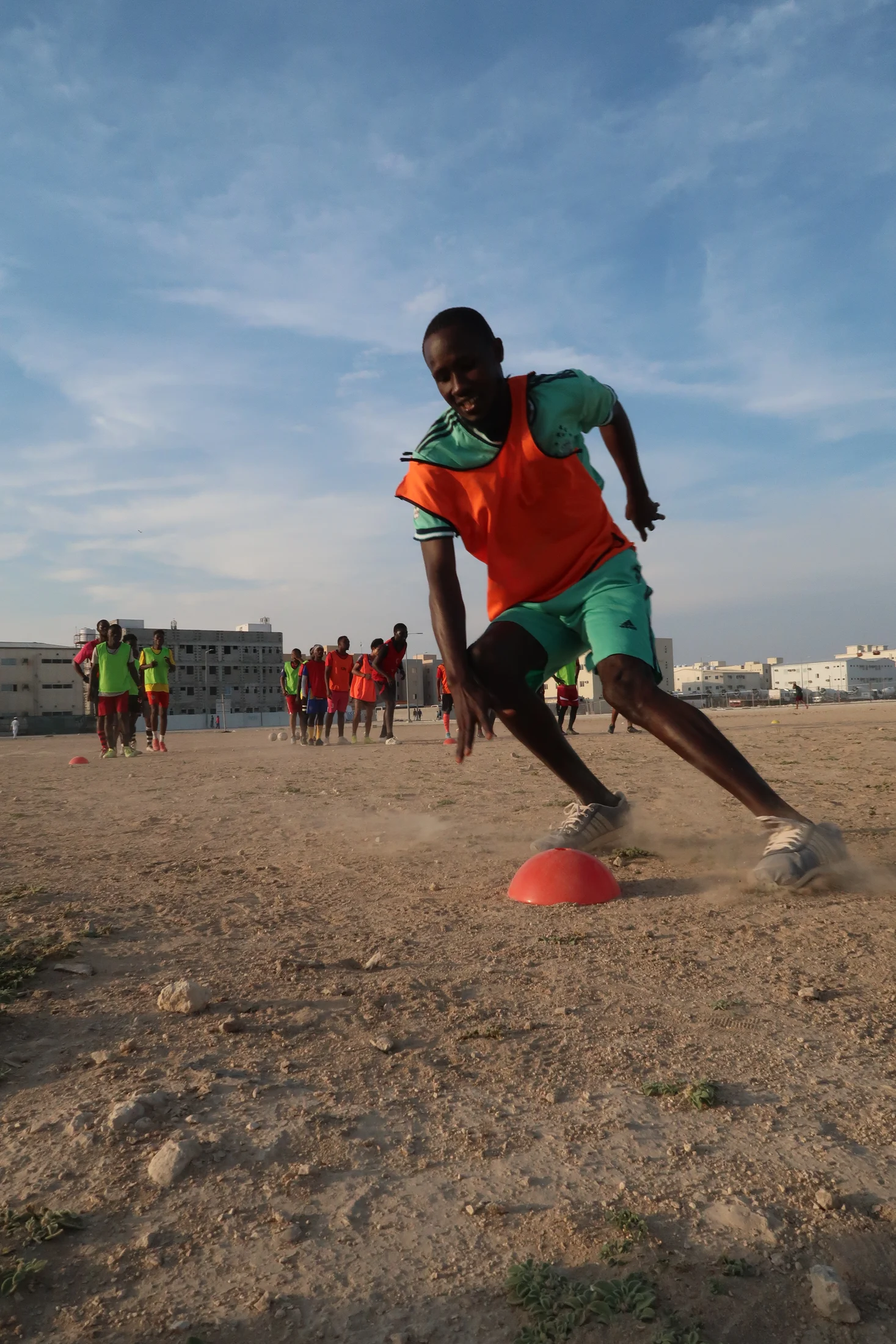 Players on a sandy football pitch in Umm Salal, Qatar